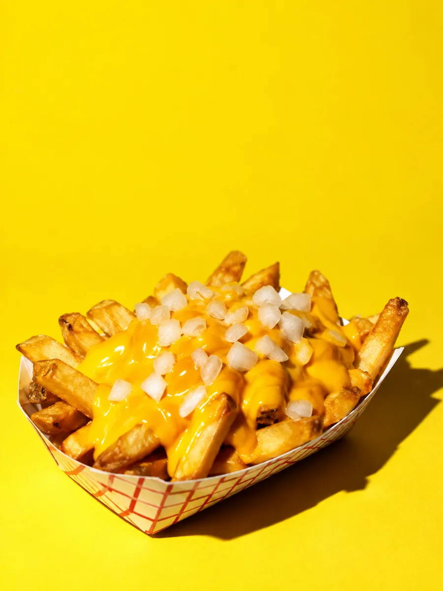 Frites nappées de cheddar sur fond jaune
