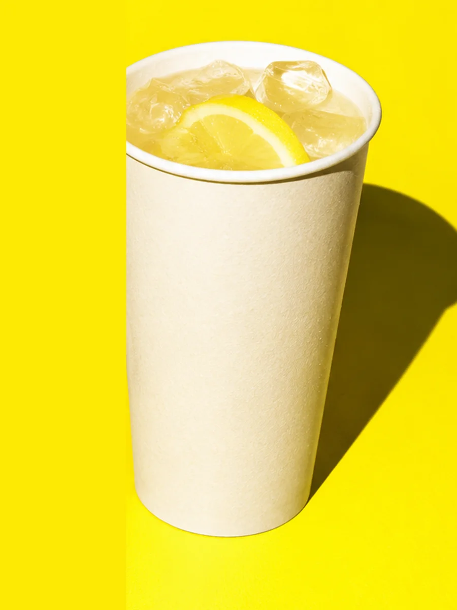 Gobelet de limonade au citron et glaçons sur fond jaune