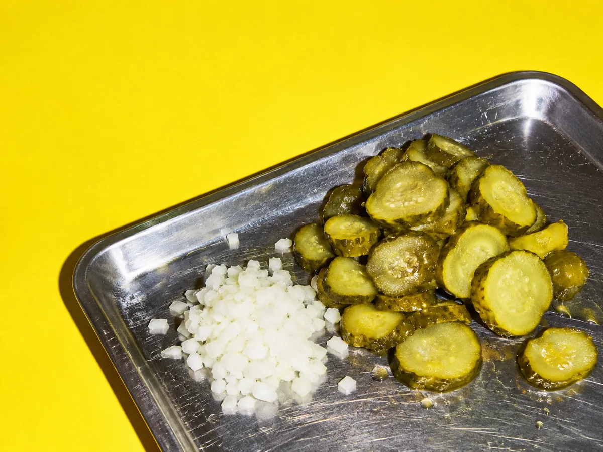 Pickles et oignons émincés sur un plateau inox
