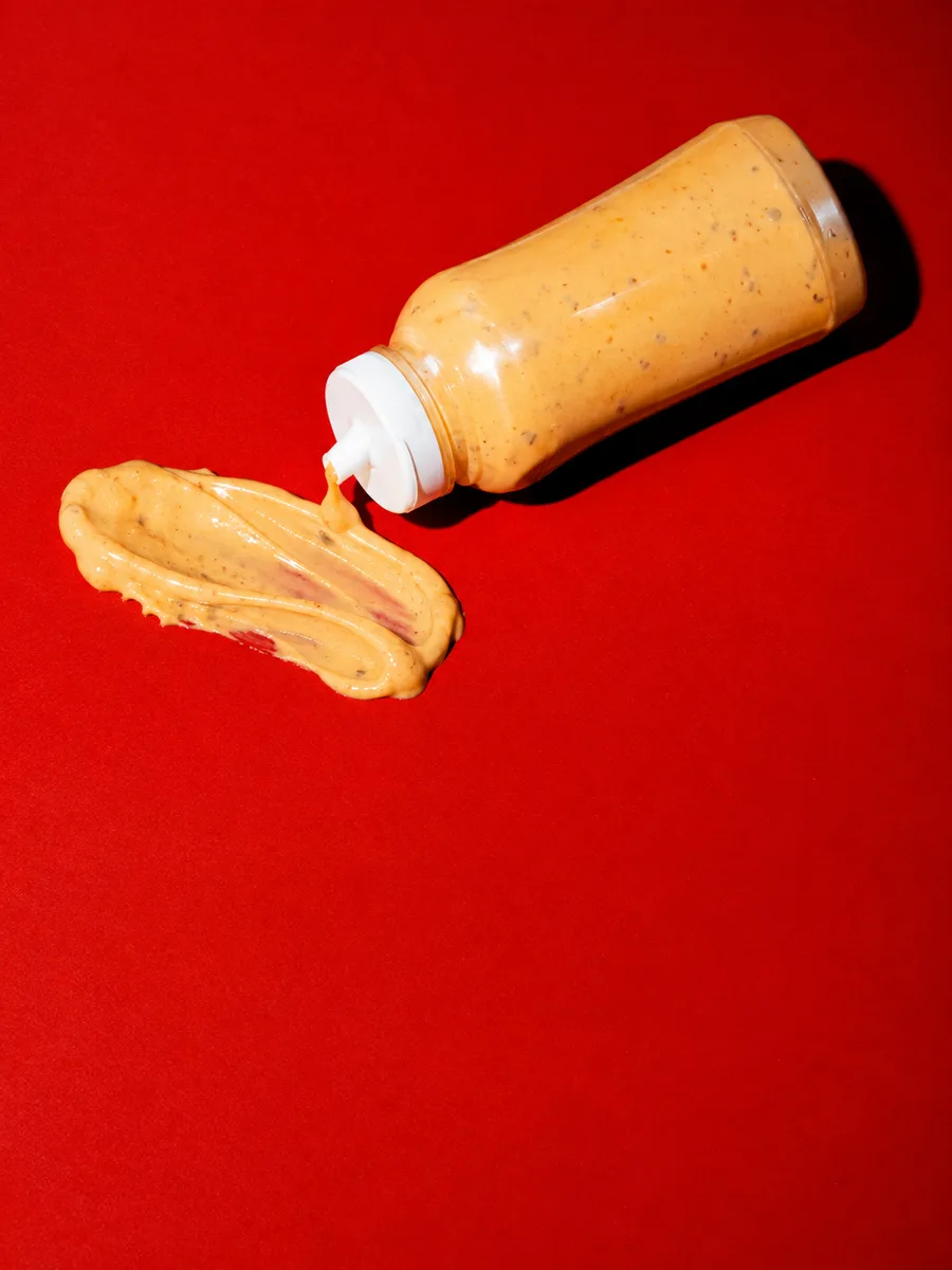 Bouteille de sauce et trace de sauce sur fond rouge